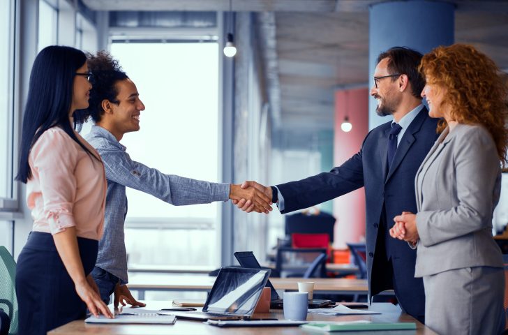 Multiethnic business teams at meeting room shaking hands. Handshake of two men. Toned concept.